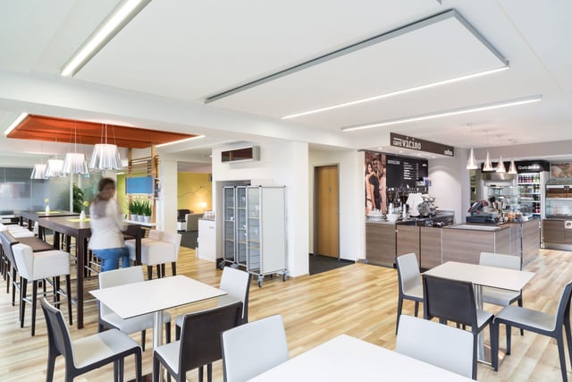 Betriebsrestaurant mit weißen Tischen, Stühlen und Kaffeetheke