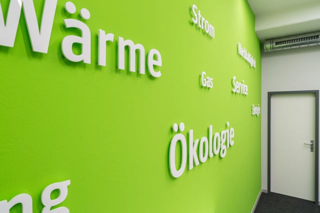 Grüne Wand mit den Wörtern „Wärme“, „Strom“, „Gas“, „Service“ und „Ökologie“