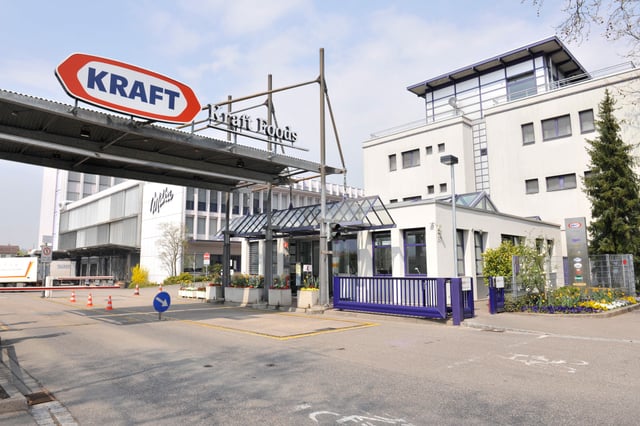 Werkszufahrt mit Vordach und dem Schild „Kraft Foods“, dahinter das Bürogebäude