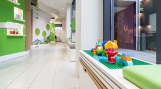 Ausstellungsraum mit grünen Wänden und Schautafeln, darauf die Überschrift: Elektromobilität – in der Region zu Hause. Vorne auf einer Fensterbank eine grüne Bauplatte mit bunten Spielsteinen.