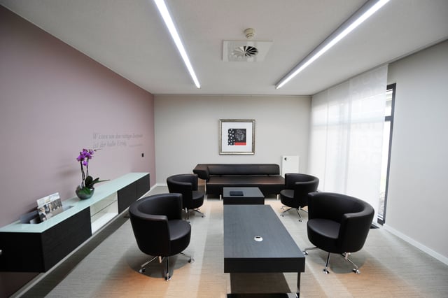 Besprechungsraum mit schwarzen Sesseln, Sofa und langem Couchtisch